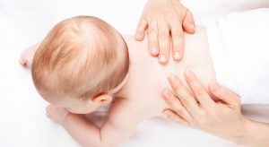 Three month baby girl is receiving back massage from a female massage therapist
